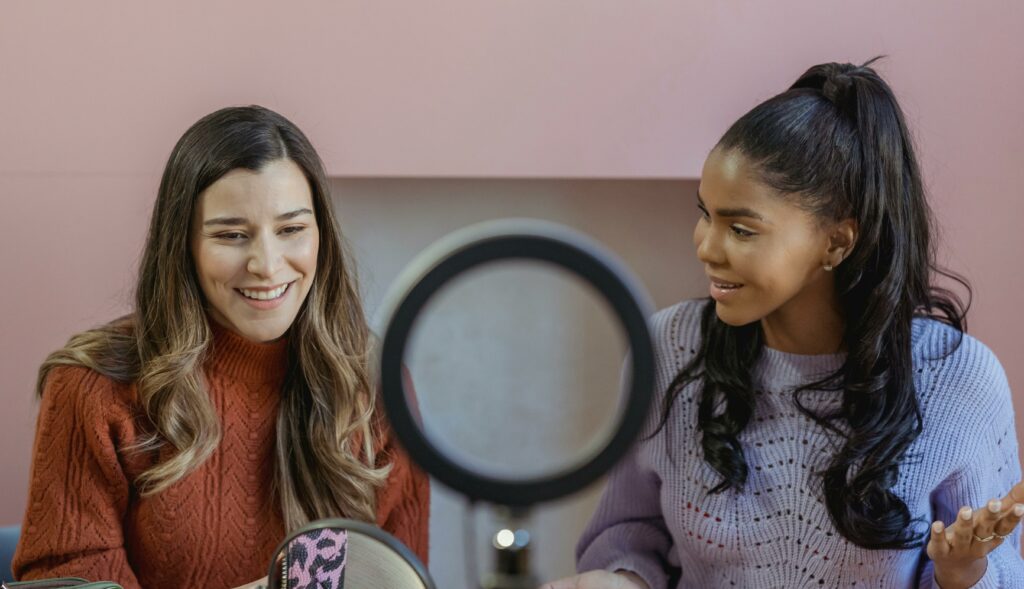 Two women chatting in a studio setting with a ring light, embracing creativity and connection.